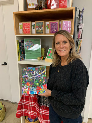 Karen Stacy holding a copy of SEEING Christmas in front of a display at one of the local shops that carries it.